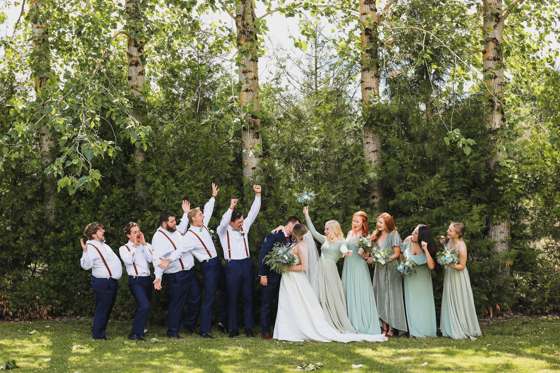 Groomsmen in white shirts, navy pants, and brown suspenders celebrating outdoors, showcasing the perfect "jacket-off" look for summer wedding suits in Orem.