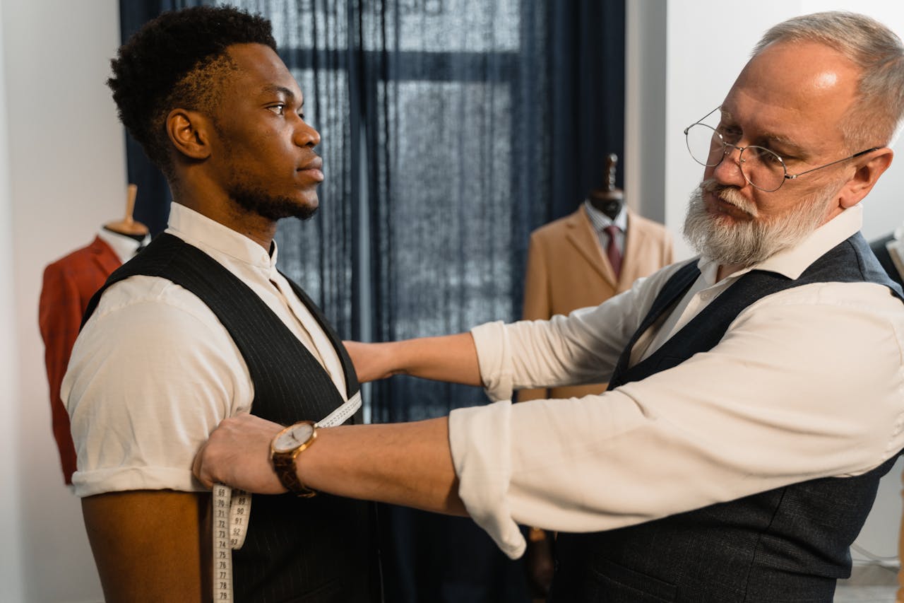 A professional tailor wrapping a measuring tape around a man's chest, demonstrating the first step in how to measure for a suit perfectly.