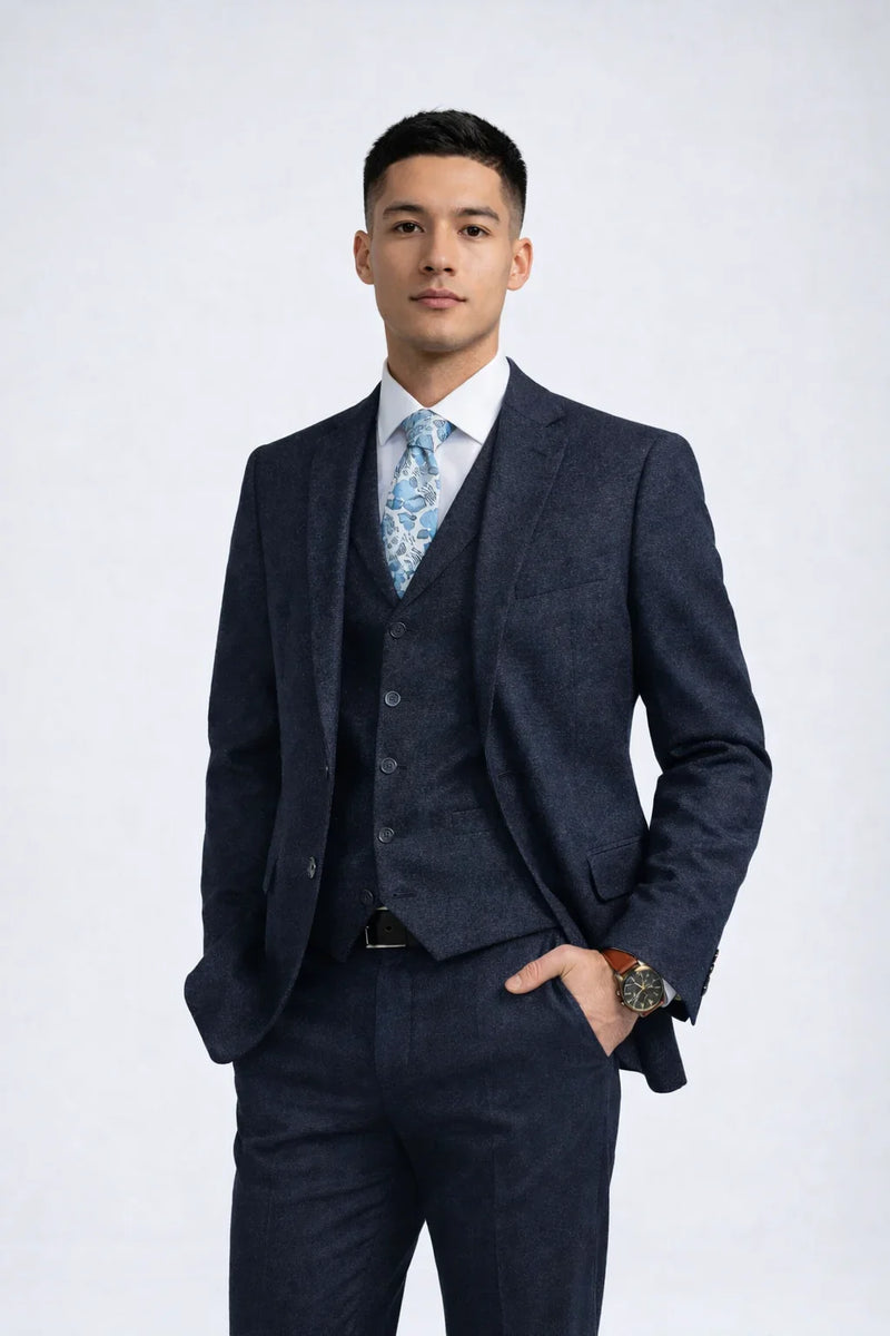 Man wearing a Men's Navy Tweed Slim Fit Suit, vest, white shirt, and floral tie, posing confidently.