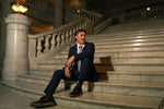 Man in a Men's Navy Slim Fit Suit sitting on elegant marble stairs in formalwear setting