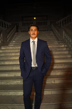 Man in a Men's Navy Slim Fit Suit and tie posing on marble stairs, formalwear fashion