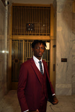 Young man in Men's Burgundy Slim Fit Suit   with floral tie standing in elegant marble hallway