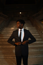 Man in Men's Black Slim Fit 2 Piece Suit with white dress shirt and black tie on plain background